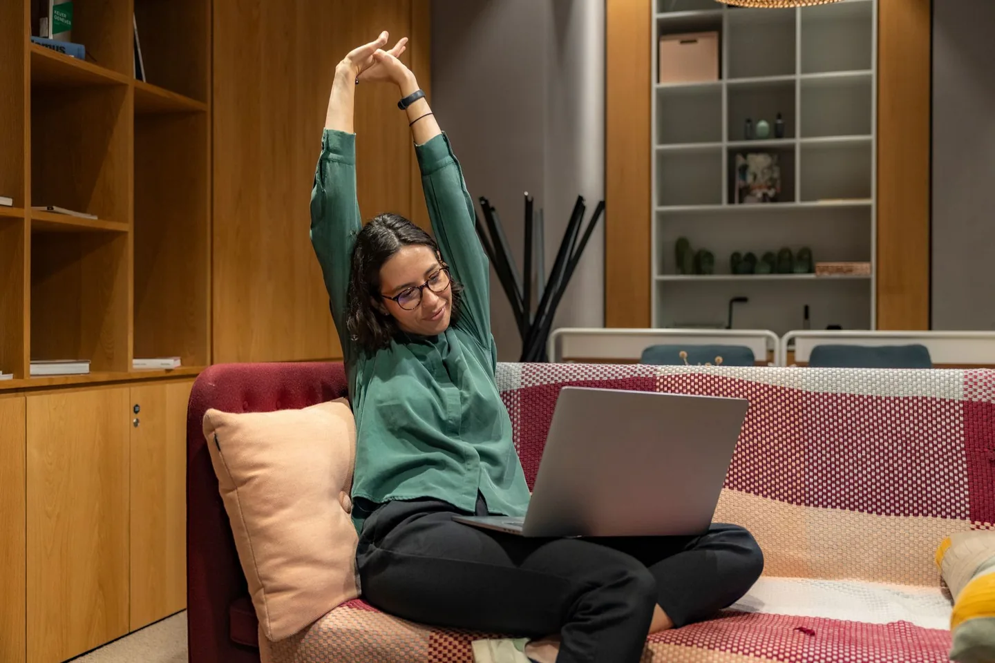 Nő a laptopos munka szünetében nyújtózik egy kanapén.